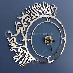 May include: A silver wall clock with Arabic calligraphy around the outer edge. The clock face is blue with silver hands and a silver center.