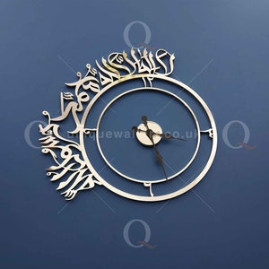 May include: A silver clock with Arabic calligraphy around the outer edge. The clock face is white with black hands and a silver center.