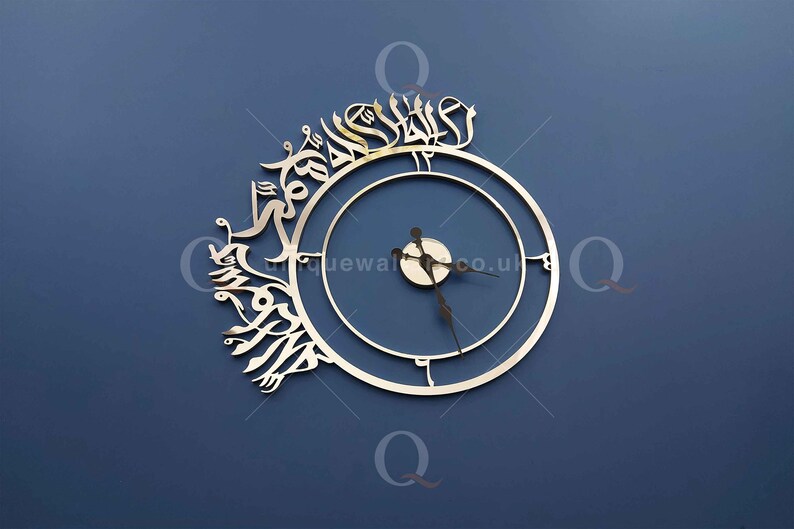 May include: A silver clock with Arabic calligraphy around the outer edge. The clock face is white with black hands and a silver center.