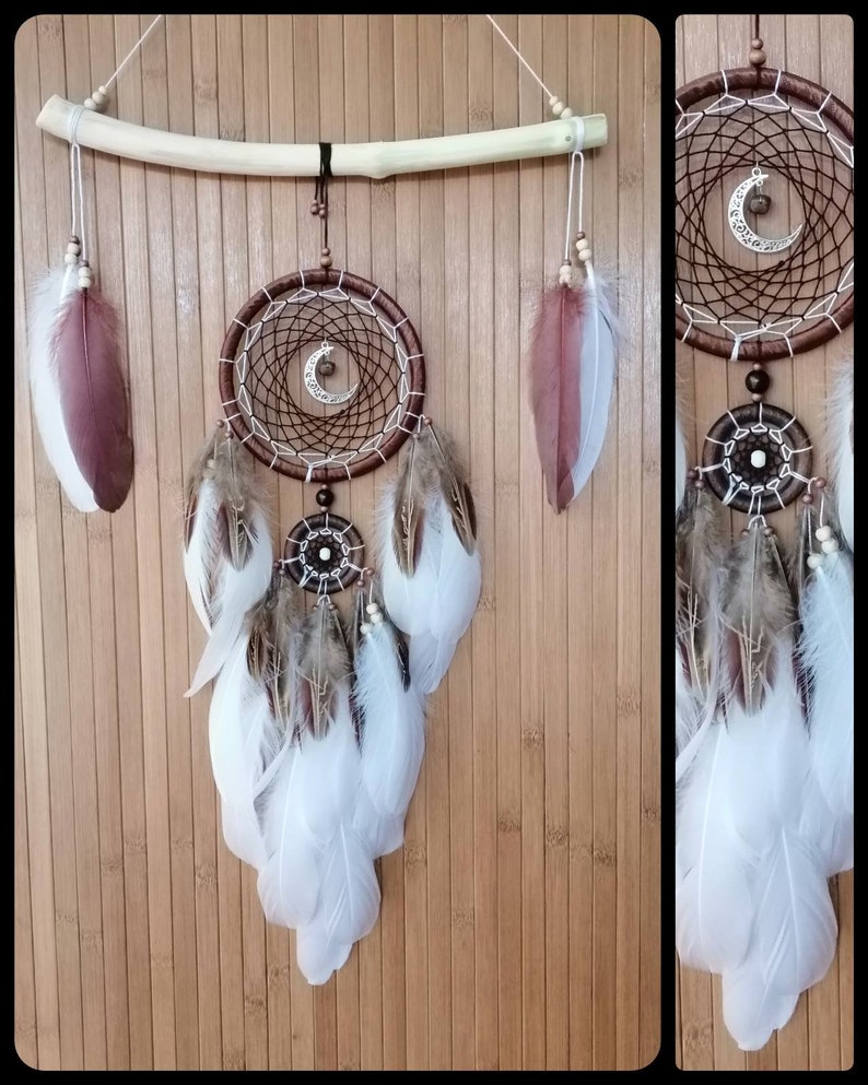 May include: A brown and white dreamcatcher with feathers hanging from the bottom. The dreamcatcher has a wooden hoop and a crescent moon charm. The feathers are white and brown.