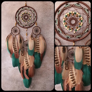 May include: A brown dream catcher with green and brown feathers. The dream catcher has a beaded center and a geometric pattern.