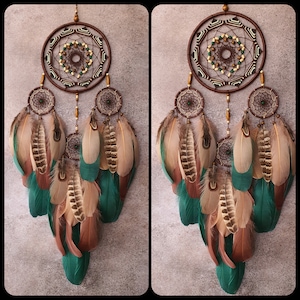 May include: A brown and green dreamcatcher with feathers. The dreamcatcher has a circular design with beads and a web-like pattern. The feathers are brown, green, and white.