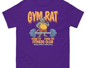 Könnte beinhalten: Ein lila T-Shirt mit dem Text "GYM RAT" in Gelb und Orange. Darunter hebt eine Cartoon-Ratte eine Langhantel. Der Text "KINDA FIT KINDA FAT FITNESS CLUB" steht darunter, mit dem Slogan "Building confidence. Building fitness."