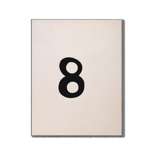 May include: A rectangular, off-white sign with a bold black number eight. The number is centered on the sign, which has a gray border. The design is simple and graphic, suitable for home decor or educational purposes.