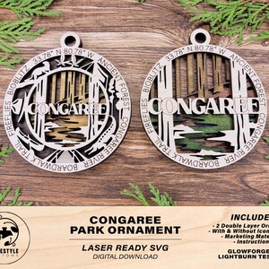May include: Laser cut wooden ornament featuring a scenic view of Congaree National Park in South Carolina. The ornament includes the park's name, coordinates, and details like the boardwalk trail, fireflies, and the Congaree River. The text "Congaree Park Ornament" and "Laser Ready SVG" is also included.
