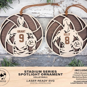 Könnte beinhalten: Zwei lasergeschnittene Holzornamente im Volleyball-Design. Die Ornamente zeigen einen Volleyballspieler in einem Trikot mit den Namen "Grant" und "Kelly" und ihren jeweiligen Nummern 9 und 8. Die Ornamente sind bereit zum Zusammenbauen und Dekorieren.
