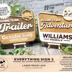 Puede incluir: Dos letreros de madera con un acabado marrón rústico. Los letreros tienen forma de letrero de carretera vintage con esquinas redondeadas y un borde blanco. El letrero superior dice "Bienvenido a nuestra aventura" con el texto "Williams Family" debajo. El letrero inferior dice "Bienvenido a nuestro remolque" con el texto "Graslie Family Established 1992" debajo. Ambos letreros presentan una escena de montaña con un lago y árboles. Los letreros están sobre pequeños caballetes de madera.