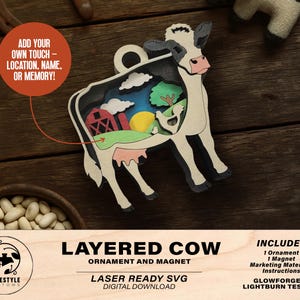 May include: A layered wooden cow ornament and magnet. The cow features a black and white design with a cut-out interior showing a farm scene with a red barn, green trees, and a yellow sun. The text says "Add your own touch - location, name, or memory!"