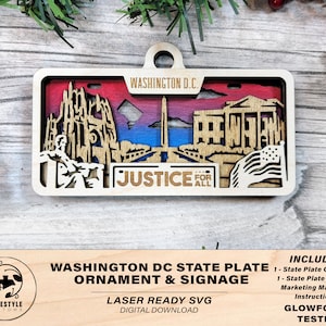 Pode incluir: Ornamento e sinalização de madeira cortada a laser da placa do estado de Washington D.C. com o Monumento a Washington e as palavras "Justice for All".