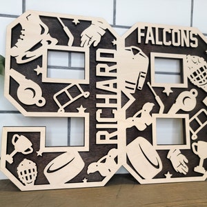 Peut inclure: Une d&eacute;coupe en bois du num&eacute;ro 98 avec des images sur le th&egrave;me du hockey. Le num&eacute;ro est peint en brun et les images sont en bois naturel. Le nom "RICHARD" est &eacute;crit verticalement sur le c&ocirc;t&eacute; gauche du num&eacute;ro et "FALCONS" est &eacute;crit horizontalement en haut du num&eacute;ro.