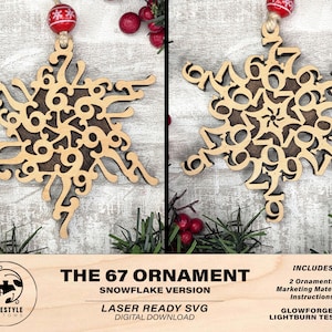 May include: Two wooden snowflake ornaments with the number 67 cut out in a decorative pattern. The ornaments are light brown with a darker brown center. Each ornament hangs from a red and white beaded string. The text "THE 67 ORNAMENT" is visible.