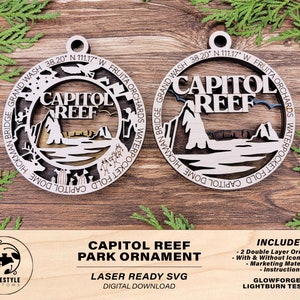 May include: Two wooden Capitol Reef Park ornaments. Each ornament is a layered design with the words "Capitol Reef" in the center, surrounded by park features and text. The ornaments are laser-cut and have a natural wood color.