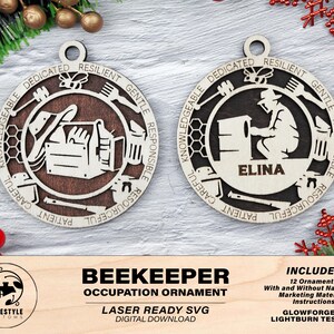 Könnte beinhalten: Zwei hölzerne Imker-Berufsschmuckstücke. Eines zeigt Werkzeuge und einen Bienenstock, das andere einen Imker mit dem Namen "ELINA". Die Ornamente sind lasergeschnitten mit den Worten "KNOWLEDGEABLE, DEDICATED, RESILIENT, GENTLE, RESPONSIBLE, RESOURCEFUL, CAREFUL, PATIENT" am Rand.
