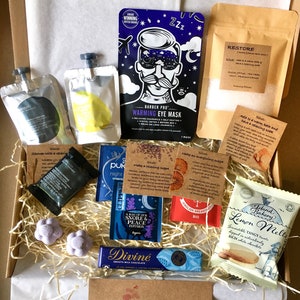 May include: A gift box filled with various self-care items, including bath salts, tea bags, chocolate, and a sleep mask. The box is lined with brown paper and straw. The text on the box reads "Especially for you".