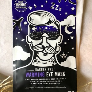 May include: A black eye mask with a cartoon illustration of a man wearing a sleep mask. The text "BARBER PRO" and "WARMING EYE MASK" is printed in white. The mask is designed to be self-heating and is made with chamomile. The text "1 MASK" is printed in white on the bottom right corner.