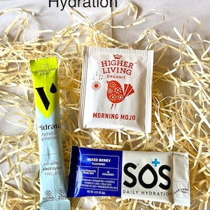 May include: A selection of hydration products, including a green and yellow "idrate" packet and a white packet with a bird design. A blue packet of "Mixed Berry" electrolyte drink mix and a white "SOS Daily Hydration" packet are also visible.