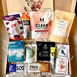 May include: A selection of wellness products presented in a gift box. Items include protein powder, energy gummies, coffee, tea, blister plasters, and hydration sachets. A card with floral design and the text "Especially for you" is also included.