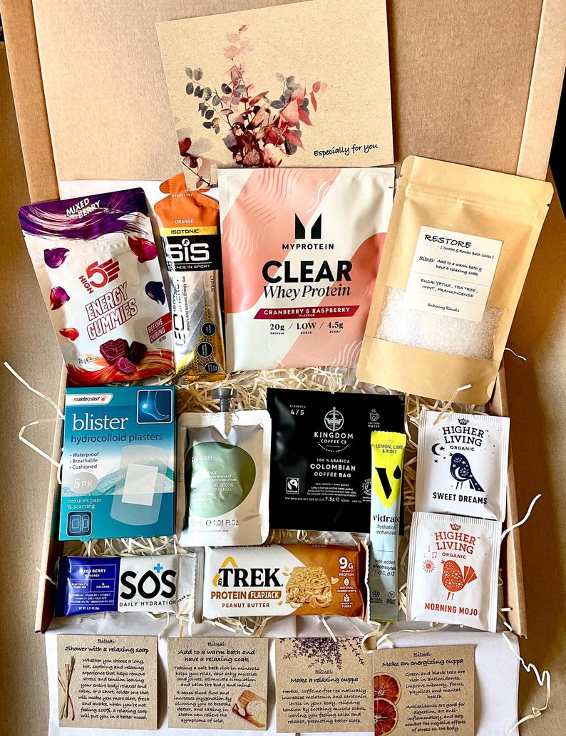 May include: A selection of wellness products presented in a gift box. Items include protein powder, energy gummies, coffee, tea, blister plasters, and hydration sachets. A card with floral design and the text "Especially for you" is also included.