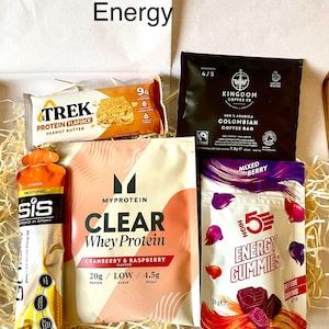 May include: A selection of energy products, including a peanut butter protein flapjack, coffee bag, whey protein powder, energy gummies, and an isotonic drink. The items are presented in a box with the word "Energy".