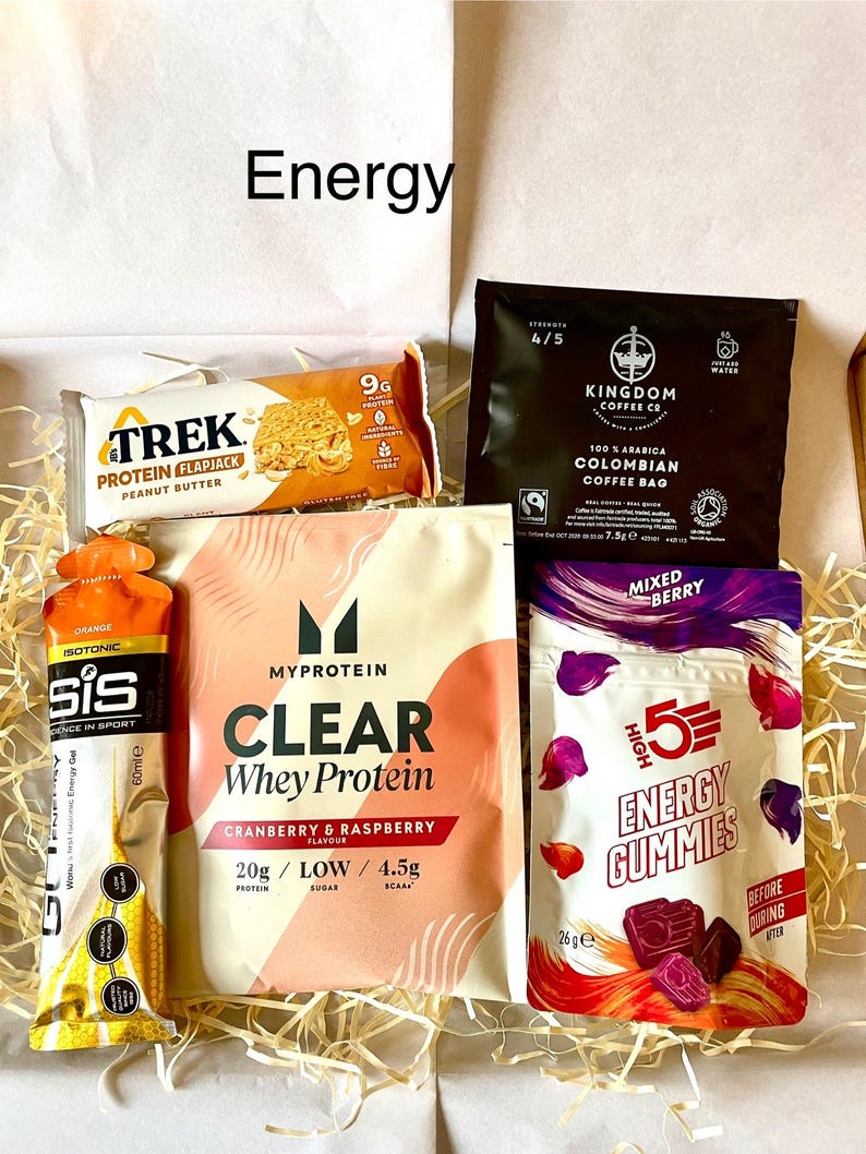 May include: A selection of energy products, including a peanut butter protein flapjack, coffee bag, whey protein powder, energy gummies, and an isotonic drink. The items are presented in a box with the word "Energy".