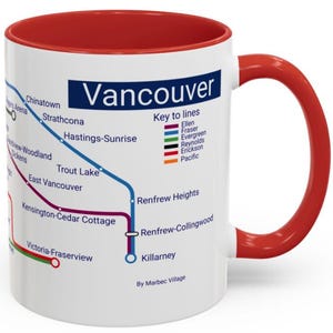 Könnte beinhalten: Eine weiße Keramiktasse mit rotem Rand und Henkel. Die Tasse zeigt eine Karte des Vancouver SkyTrain-Systems mit den Namen der Stationen und Linien. Der Text "Vancouver" ist oben auf der Tasse in Blau gedruckt. Der Text "Key to lines" ist unter der Karte in Schwarz gedruckt. Der Text "By Marbec Village" ist unten auf der Tasse in Schwarz gedruckt.