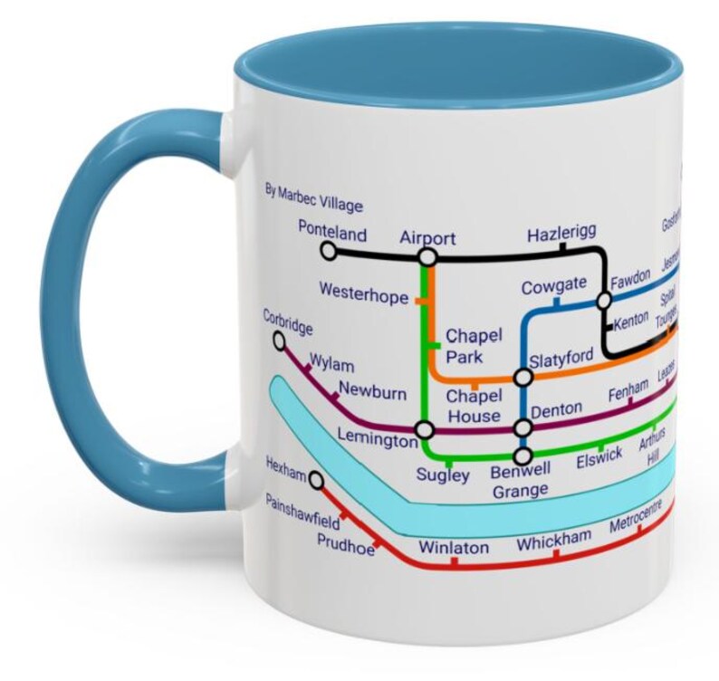 Puede incluir: Taza de cer&aacute;mica blanca con borde y asa azules. La taza presenta un mapa estilizado del sistema de metro de una ciudad con nombres de estaciones y l&iacute;neas de colores.