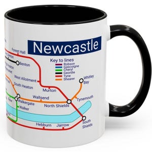 Puede incluir: Taza de cer&aacute;mica blanca con asa y borde negros. La taza presenta un mapa del sistema de metro de Newcastle con el t&iacute;tulo "Newcastle" y una clave para las l&iacute;neas. Las l&iacute;neas est&aacute;n codificadas por colores y etiquetadas con nombres como Robson, Gascoigne, Cheryl, Geordie, Tyne y Shearer.