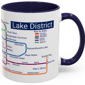 May include: White ceramic mug with a navy blue interior and handle. The mug features a colorful map design of the Lake District, with place names and key lines. The text "Lake District" is displayed prominently.