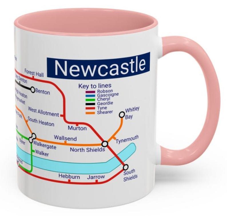 Puede incluir: Taza de cer&aacute;mica blanca con borde y asa de color rosa. La taza presenta un mapa del sistema de metro de Newcastle con el t&iacute;tulo "Newcastle" en texto azul. El mapa incluye los nombres de las estaciones y las l&iacute;neas, con una clave de l&iacute;neas que muestra los colores de cada l&iacute;nea.