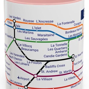 Puede incluir: Una taza de cer&aacute;mica blanca con un borde rosa presenta un mapa estilizado del sistema de metro de Montreal. El mapa incluye los nombres de las estaciones en franc&eacute;s, como "Les Vardes", "L'Islet" y "La Villiaze".