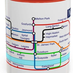 Puede incluir: Una taza de cer&aacute;mica blanca con un borde rojo presenta un mapa colorido del sistema de metro de Newcastle upon Tyne. El mapa incluye nombres de estaciones como Jesmond, Haymarket y Byker.