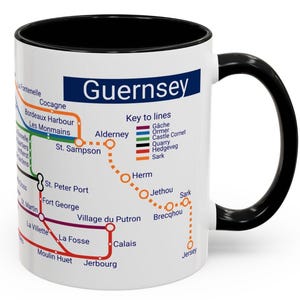 Puede incluir: Taza de cer&aacute;mica blanca con asa negra. La taza presenta un mapa de las Islas del Canal con el t&iacute;tulo "Guernsey" y una clave de l&iacute;neas. El mapa muestra las islas de Alderney, Herm, Sark, Jethou y Jersey.