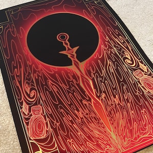 May include: A print featuring a stylized sword design. The artwork has a black background with a large black circle. The sword is gold, and the surrounding design is red and gold.