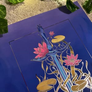 May include: A blue and silver sword with a gold handle is surrounded by pink and white water lilies and gold lily pads on a blue background.