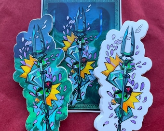 Puede incluir: Tres pegatinas con un diseño de tridente estilizado con un centro de gema geométrica, una explosión amarilla y acentos florales morados. Una pegatina está sobre una imagen de fondo de un templo. Las pegatinas están sobre una superficie roja.