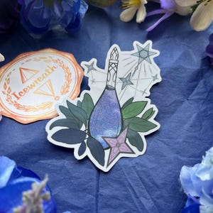May include: A die-cut sticker featuring a purple glittery potion bottle surrounded by dark green leaves and a light purple star-shaped flower. The design includes thin black line art of a starburst and smaller stars in the background.