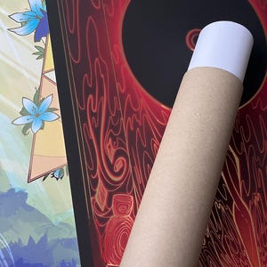 May include: A rolled-up poster with a black circle in the center surrounded by red and gold swirling designs. The poster is being held in a brown cardboard tube.