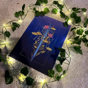 May include: A blue and gold print of a sword surrounded by water lilies and leaves. The print is on a dark blue background.
