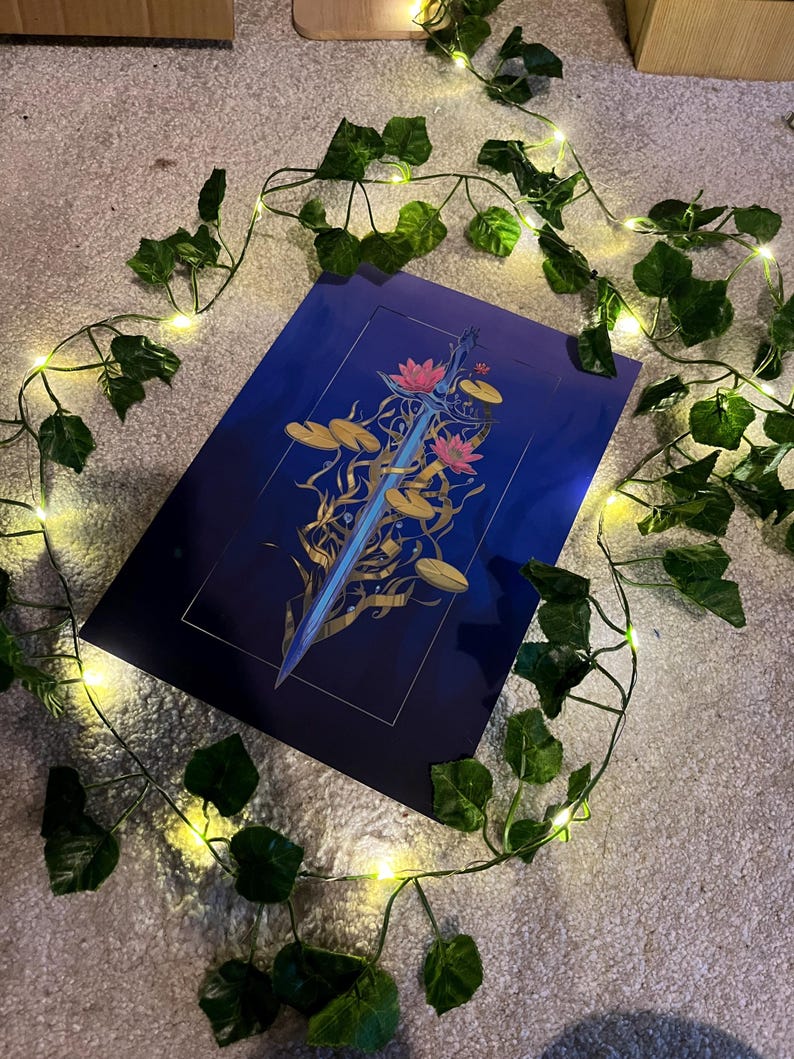 May include: A blue and gold print of a sword surrounded by water lilies and leaves. The print is on a dark blue background.