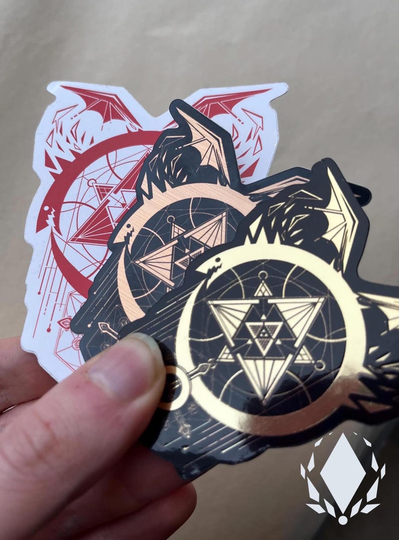 Similar to the previous photo, a hand holds the three variants of the sticker, but at a slight angle, to show them reflected by light. Icewreath's shop logo is placed in the corner.