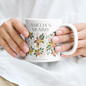 May include: White ceramic mug with a floral design featuring orange blossoms, lemons, and bees. The mug has the text "Amelia's Mummy" and "Little Grey London" printed on it.