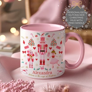 Pode incluir: Caneca de Natal rosa personalizada com alça rosa. A caneca apresenta um tema de Quebra-Nozes com um Quebra-Nozes, um rei rato e uma bailarina. A caneca diz "Alexandra acredita na magia do Natal".