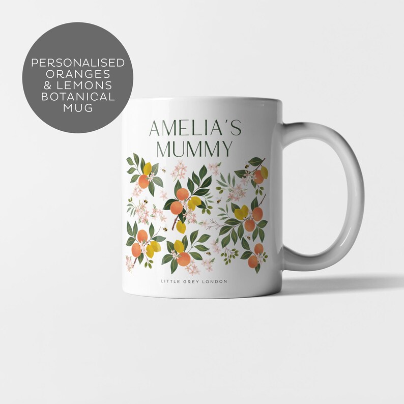 May include: White ceramic mug with a floral design featuring oranges, lemons, and bees. The text "Amelia's Mummy" is printed on the mug.