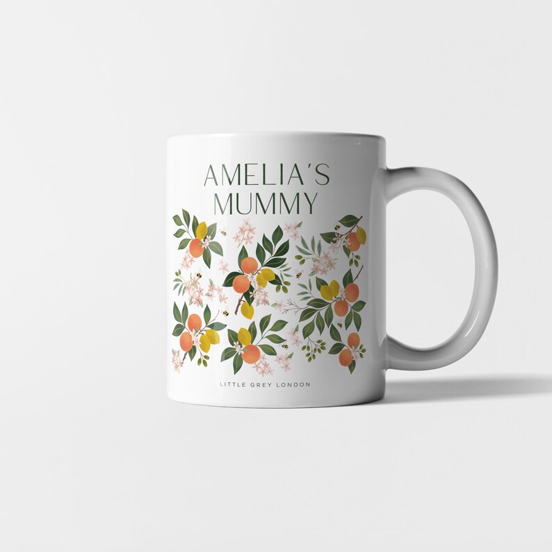 May include: White ceramic mug with a floral design featuring orange blossoms, lemons, and bees. The text "Amelia's Mummy" is printed on the mug.