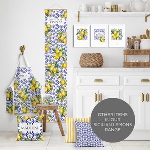 Puede incluir: Un conjunto de art&iacute;culos de decoraci&oacute;n para el hogar con un patr&oacute;n de azulejos azules y blancos con limones y flores. El conjunto incluye un tapiz de pared, un delantal de cocina, una almohada y una taza. Todos los art&iacute;culos est&aacute;n decorados con el texto "How tall are the Joneses?" y "Madeline".