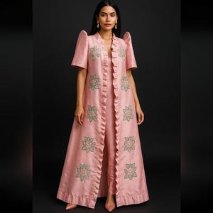May include: A light pink ensemble featuring a long, open-front coat with ruffled edges and short sleeves, paired with matching pants. The coat and pants are adorned with embroidered floral patterns. The outfit is made of a silky material.