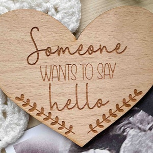 May include: Wooden heart-shaped sign with the text "Someone wants to say hello" and a leafy design around the edges.