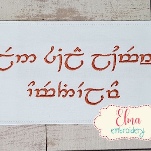 May include: White fabric with orange embroidery of the text "It'm  bjt  tjmm  imbkjt". The fabric has a white border and the text is in a cursive font.