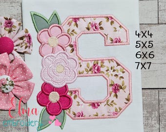 May include: Embroidered floral letter "S" with pink roses on a white background, accompanied by pink flower bows. The letter is outlined in pink and surrounded by embroidered flowers and leaves. Sizes available: 4x4, 5x5, 6x6, 7x7.