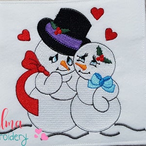Pu&ograve; includere: Disegno ricamato di due pupazzi di neve che si abbracciano, con fiocchi rossi e blu, con cuori e dettagli di agrifoglio. Il testo "Elma embroidery" &egrave; in basso.